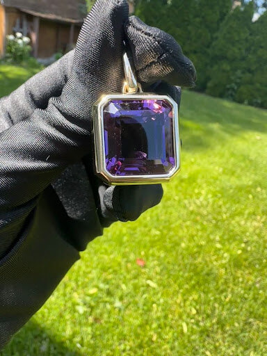 Colored stone pendant held outdoors