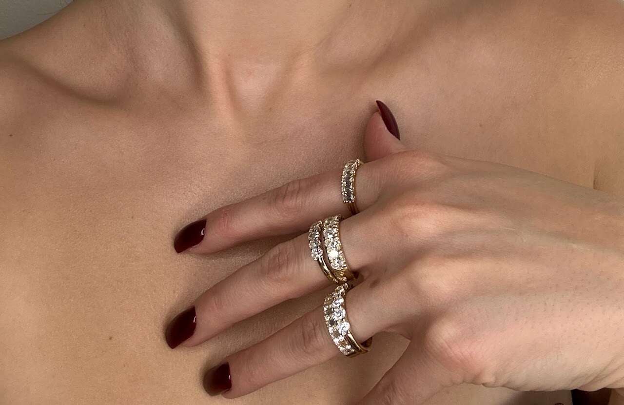 Wedding and engagement rings stacked on a hand in soft light